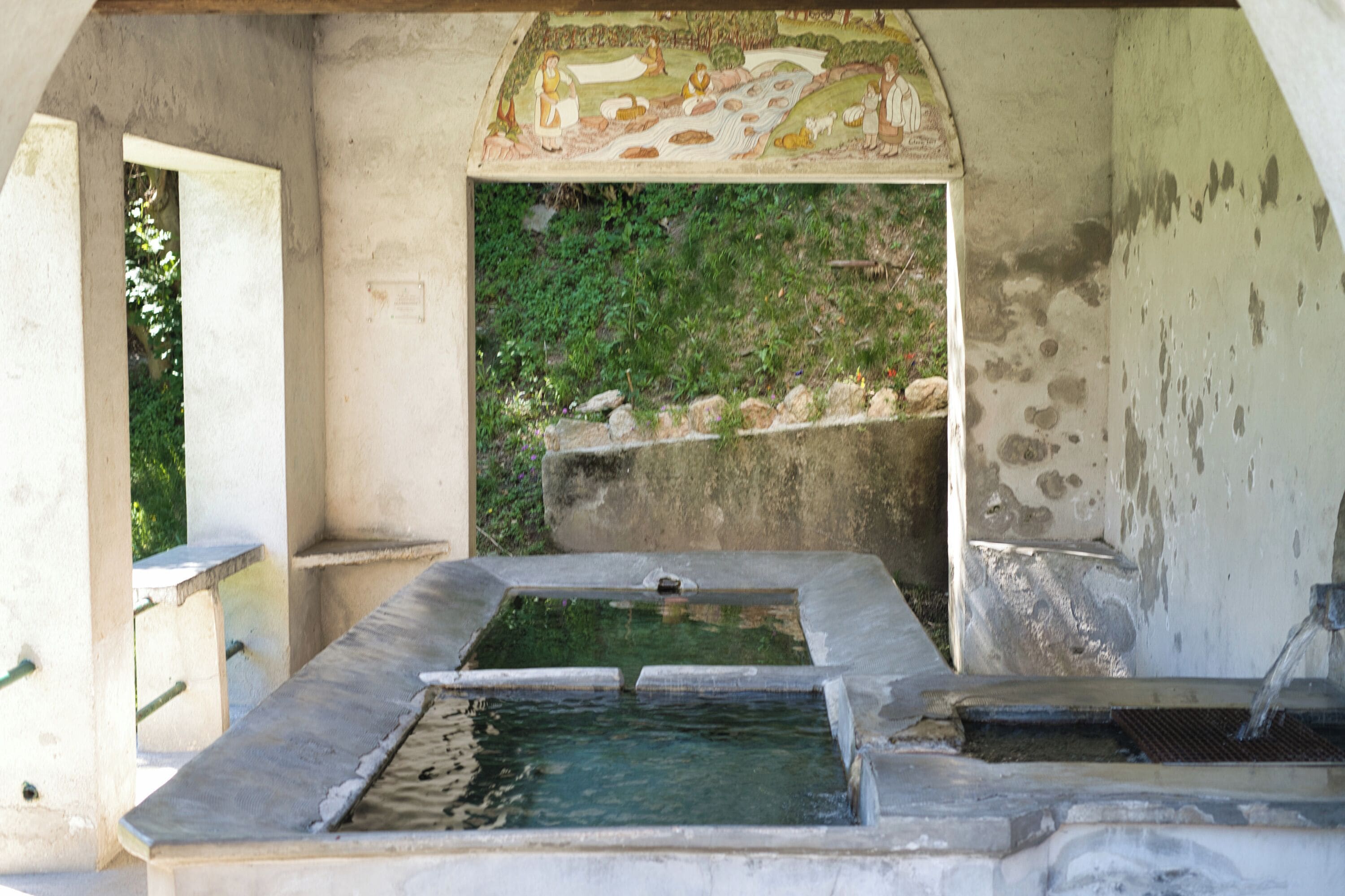 A stone structure with a water feature and a mural.