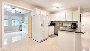 Eine moderne Küche mit weißen Schränken, einer Granitarbeitsplatte und einer eingebauten Mikrowelle.