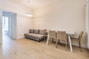 Een moderne woonkamer met een bank, eettafel en stoelen.