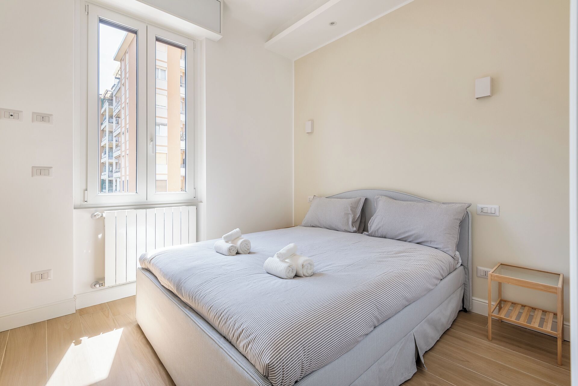 Una camera da letto con un letto, una finestra e un pavimento in legno.