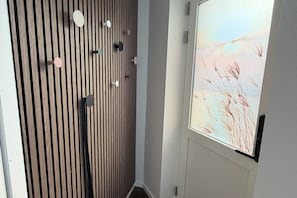 A room with a wooden slat wall, a door with a frosted glass window, and a wall-mounted light fixture.