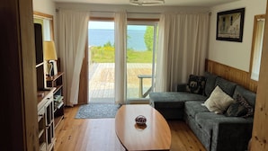 A room with a wooden floor, a sofa, a table, and a view of the sea through a glass door. - Welcome to The Cedars.
Beautifully maintained waterfront quaint log cabin (Northeastern Manitoulin and the Islands)