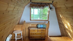 A room with wooden walls, a sloped ceiling, a bed with a plaid bedspread, a wooden dresser, a small round table, and a window with curtains. - Welcome to The Cedars.
Beautifully maintained waterfront quaint log cabin (Northeastern Manitoulin and the Islands)