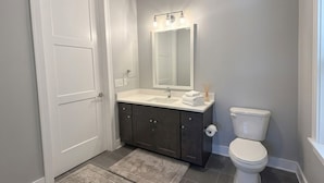 Un bagno con una porta bianca, mobili scuri, un water bianco e uno specchio illuminato.