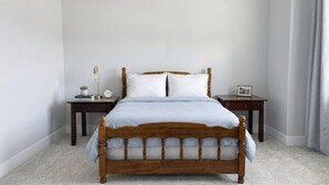 Una camera da letto con un letto di legno, due comodini, un tavolino e una piccola pianta.
