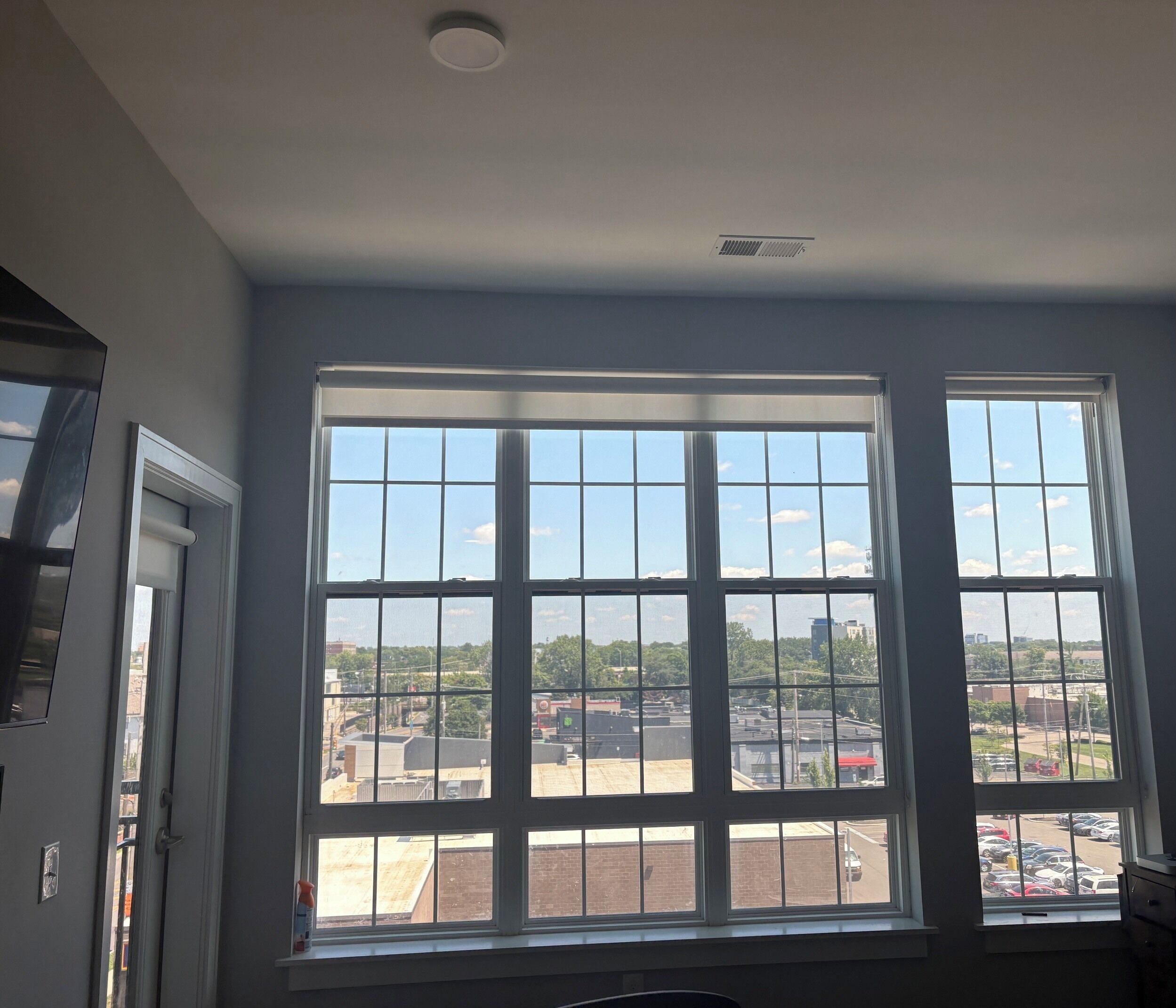 A room with a large window offering a view of a parking lot and buildings.