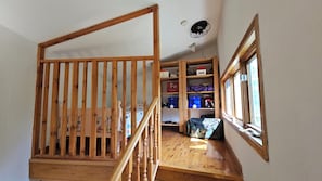 A wooden staircase with a railing, a window, and a shelf with storage boxes.
