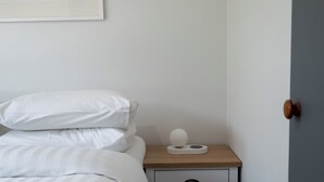 Un lit bien fait, avec une literie blanche, une table de chevet avec une lampe et un tiroir.