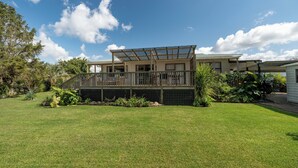 Une maison à deux étages avec une terrasse couverte et une cour clôturée.