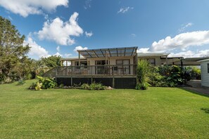 A two-story house with a covered deck and a fenced yard. - Calden Cottage - Ngunguru Holiday Home (Whangarei)