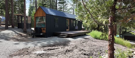 A cabin with a wooden deck, surrounded by trees.