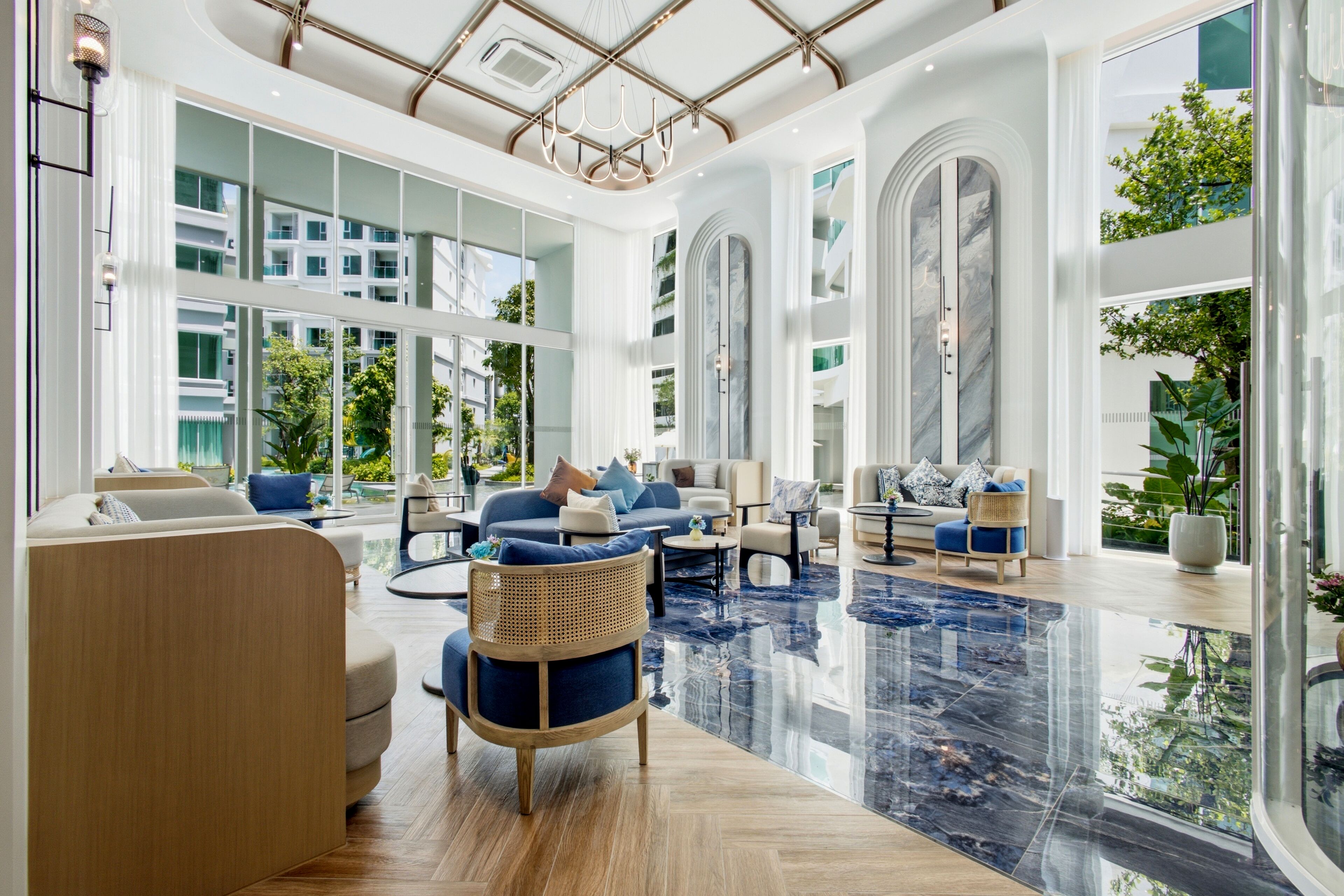 A spacious hotel lobby with a high ceiling, large windows, and a reflective marble floor.