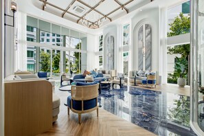 A spacious hotel lobby with a high ceiling, large windows, and a reflective marble floor. - Title Serenity Naiyang: pool access (Thalang District)