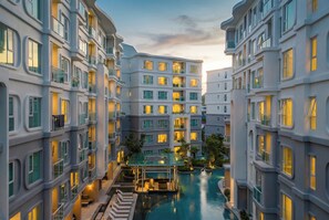 A modern hotel with multiple floors, balconies, and a central swimming pool area. - Title Serenity Naiyang: pool access (Thalang District)
