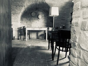 A room with a brick wall, a desk, two chairs, a table, and a lamp. - Casa Briga: A historic 19th-century noble residence. (Montesilvano Colle)