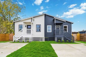 A two-story house with a front porch, a small deck, and a well-maintained lawn. - Executive 3BR  Near Downtown, Port & LBJ Hospital (Houston)