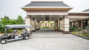 A building entrance with a covered walkway, a golf cart, and a landscaped area with plants.