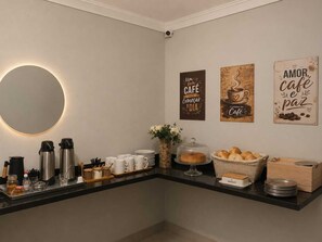 A breakfast bar with coffee makers, cups, and pastries. - Pousada Aviacao (Praia Grande)