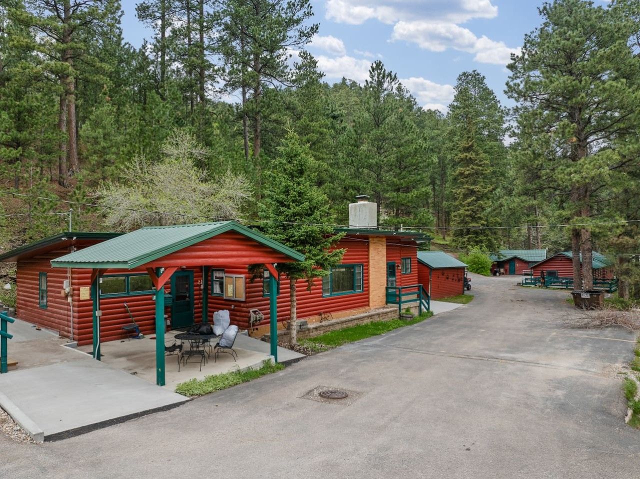 Una fila di baite di legno con tetti verdi, un tavolo da picnic e un vialetto lastricato.