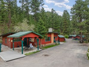 Filera de cabanes de fusta amb teulades verdes, una taula de picnic i un camí pavimentat.