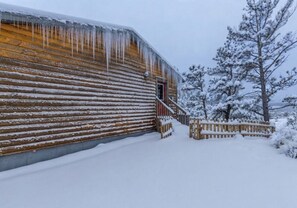 Una baita di legno con tetto imbiancato dalla neve e stalattiti sporgenti.