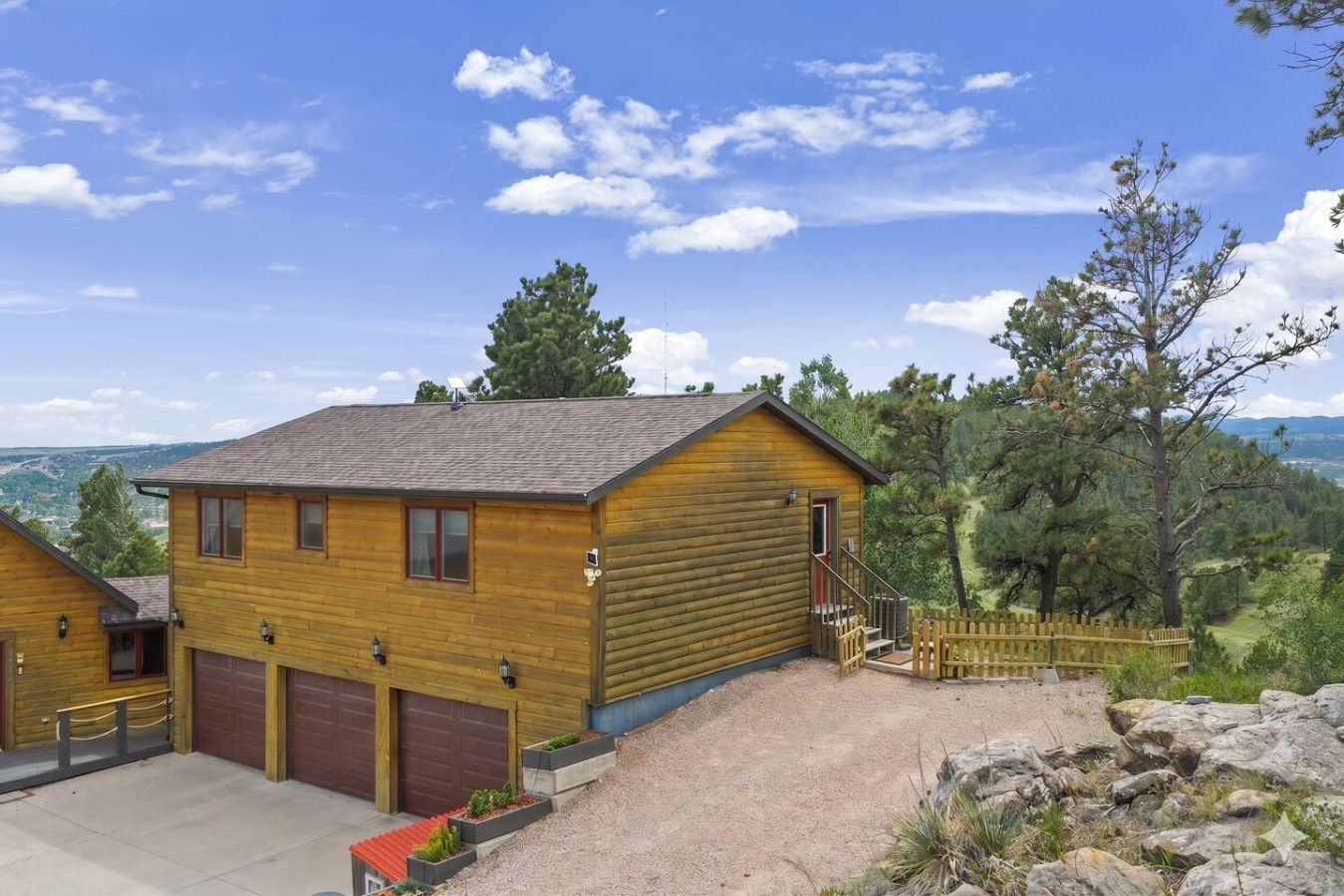 Une cabane en bois avec un garage, une véranda et une vue sur le paysage environnant.