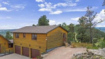 Une cabane en bois avec un garage, une véranda et une vue sur le paysage environnant.