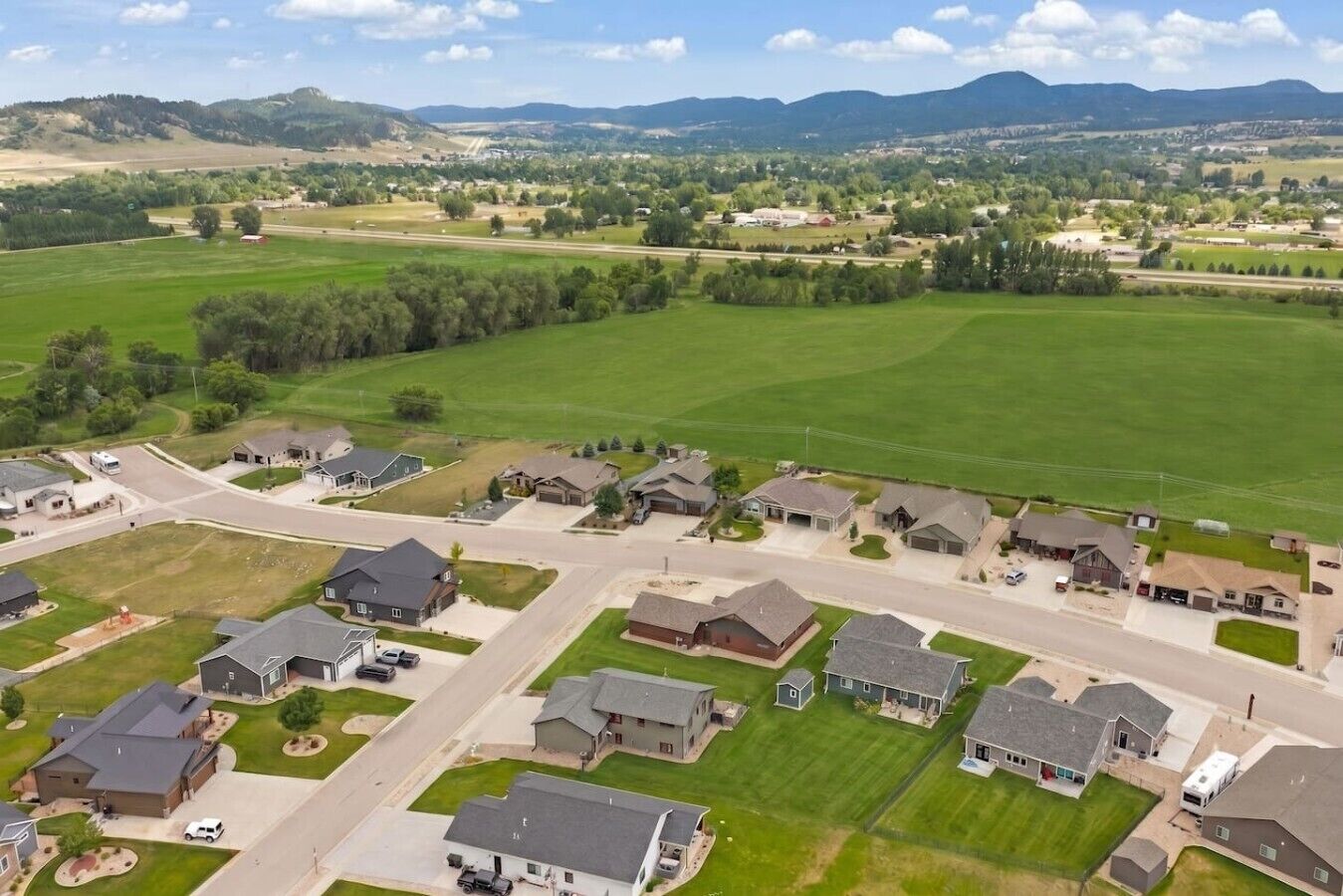 A residential area with houses, roads, and green fields.