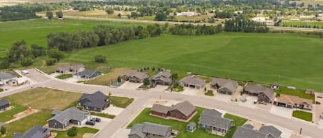 A residential area with houses, roads, and green fields.