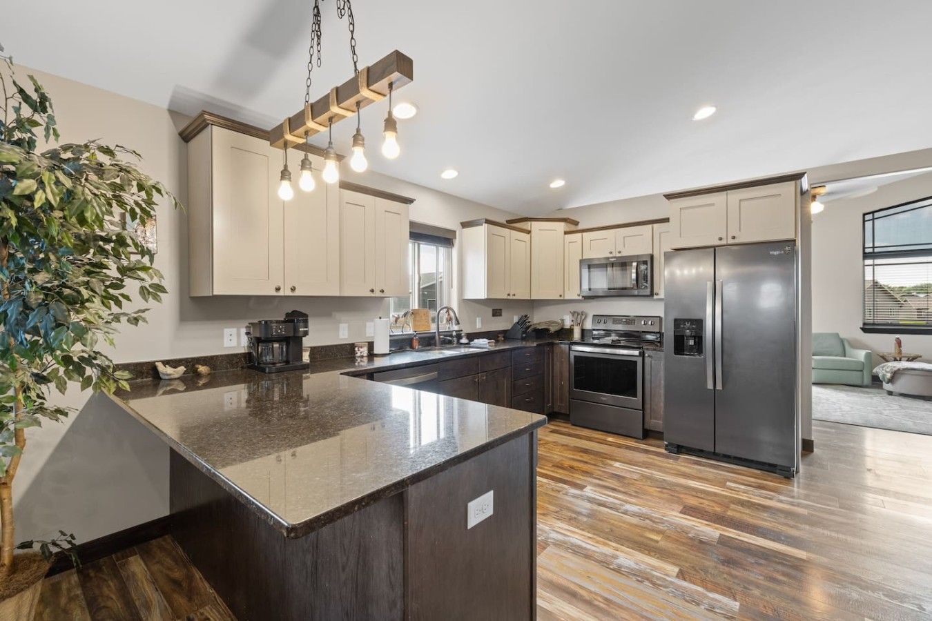 A modern kitchen with a central island, stainless steel appliances, and a hanging light fixture.