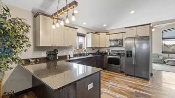 A modern kitchen with a central island, stainless steel appliances, and a hanging light fixture.