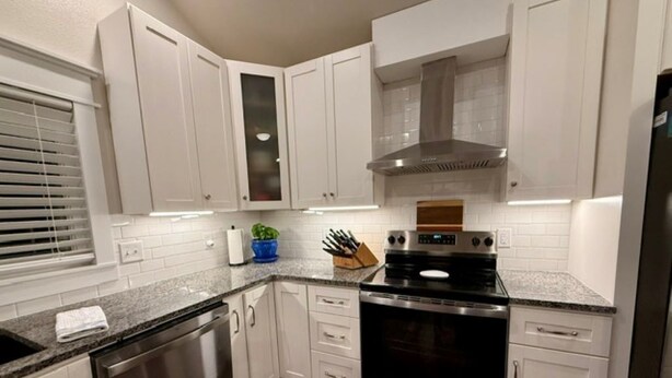 A modern kitchen with white cabinets, stainless steel appliances, and a granite countertop. - Two Tired Inn: Cozy, convenient, hot tub, fire pit, by trails, museums, downtown (Bentonville)