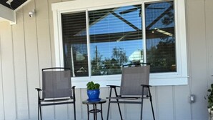 A patio area with two chairs, a small table, and a potted plant. - Two Tired Inn: Cozy, convenient, hot tub, fire pit, by trails, museums, downtown (Bentonville)