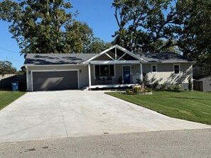 Ein eingeschossiges Haus mit Garage, Veranda und einem gepflegten Rasen.