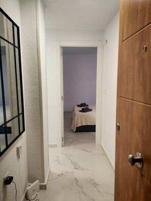 A hotel room with a bed, a wooden door, and a white wall with a textured finish. - La Casa Datskovi Beach Apartments (Torre Vieja)