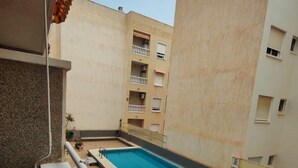 Um edifício residencial com piscina, varandas e chão de azulejos.
