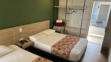 Een hotelkamer met twee bedden, een bureau, een stoel, een kledingrek en uitzicht.