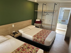 Ett hotellrum med två sängar, ett skrivbord, en stol, en klädstång och utsikt över omgivningarna.