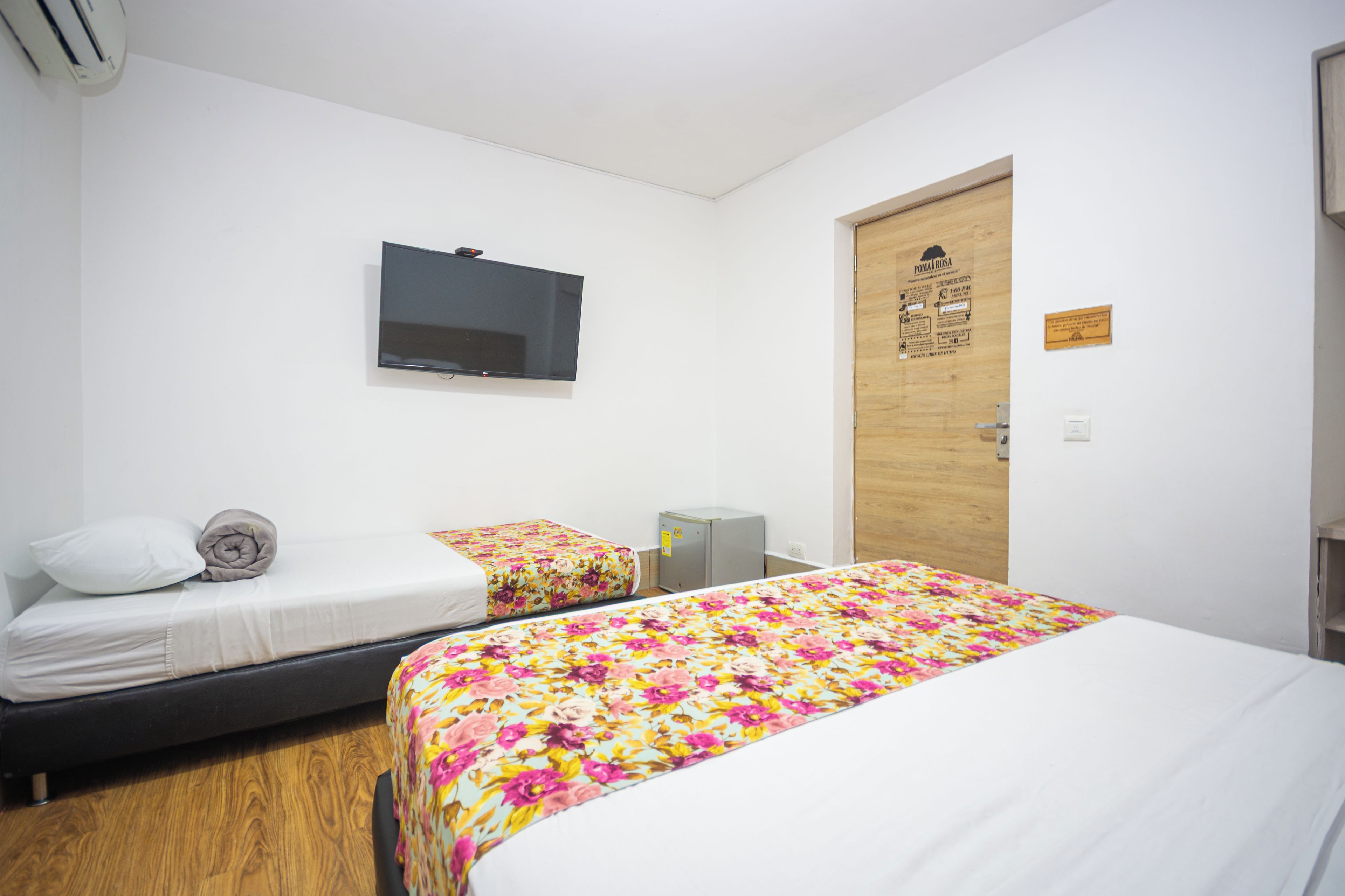 Une chambre d’hôtel avec deux lits, une télévision, une porte en bois et un petit bureau.