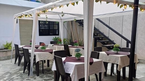 Une terrasse extérieure avec des tables et des chaises, un espace salon couvert et un escalier en arrière-plan.