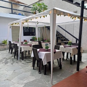 An outdoor patio with tables and chairs, a covered seating area, and a staircase in the background. - HOTEL BOUTIQUE POMA ROSA (Medellin)
