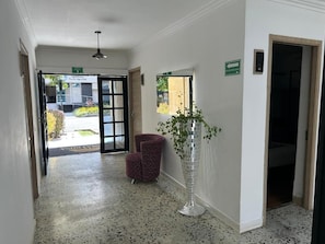 A hallway with a patterned floor, a potted plant, and a chair. - HOTEL BOUTIQUE POMA ROSA (Medellin)