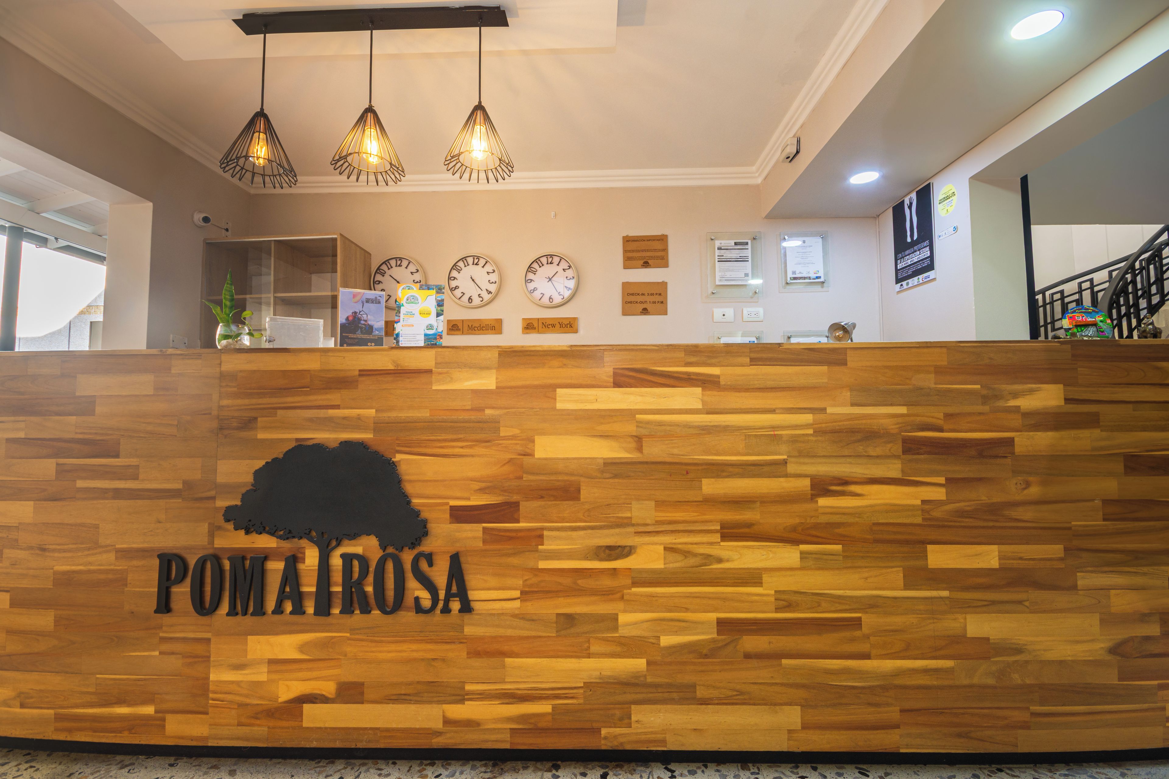 Una recepción con un diseño de panel de madera y un logotipo. Hay relojes en la pared, una planta y un cartel.