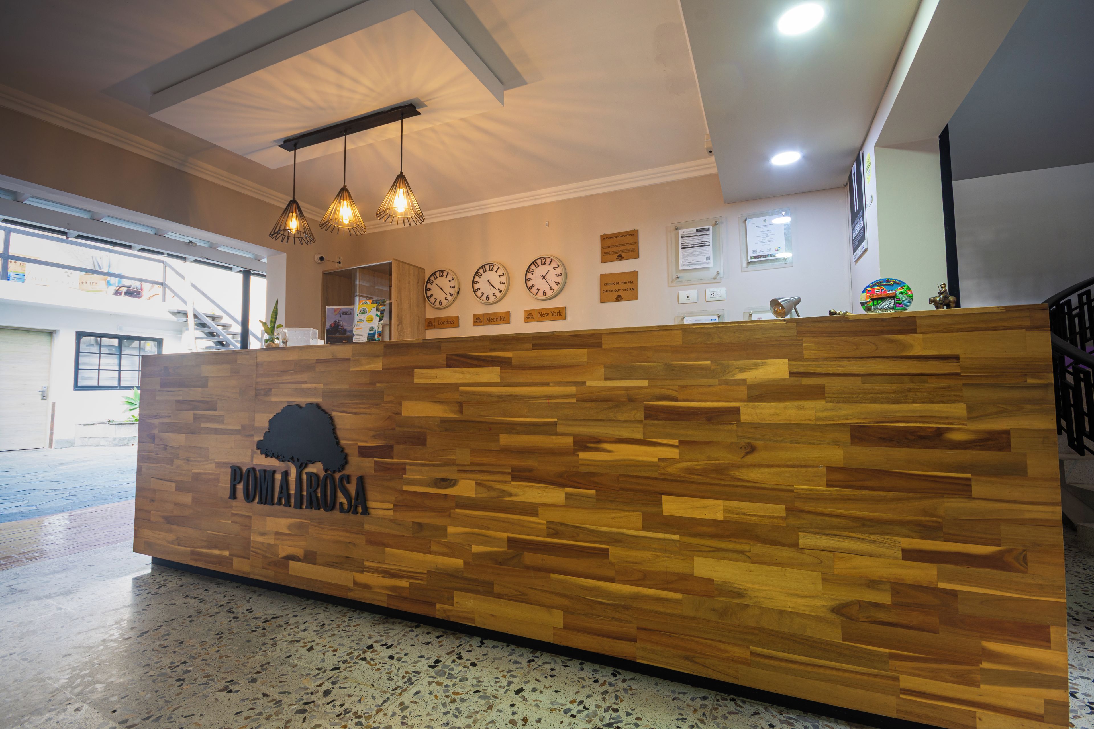 Un mostrador de recepción con paneles de madera, un logotipo, relojes y una pequeña estatua en la pared.