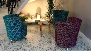Un intérieur moderne avec un escalier, un coin salon doté de fauteuils à motifs, une petite table et une plante.