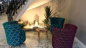 Een modern interieur met een trap, een zithoek met gestreepte stoelen, een klein tafeltje en een plant.