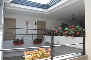A modern interior with a glass ceiling, potted plants, and a metal railing. - HOTEL BOUTIQUE POMA ROSA (Medellin)
