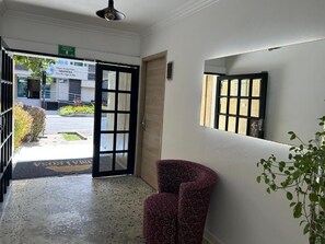 A hotel entrance with a reception desk, a door leading outside, and a mirror on the wall. - HOTEL BOUTIQUE POMA ROSA (Medellin)