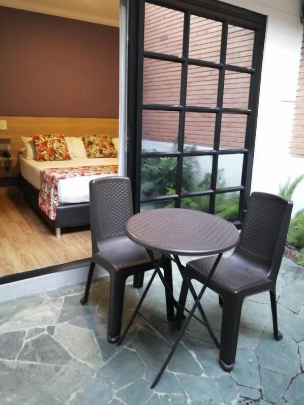 A room with a bed, a window, and a table with two chairs. - HOTEL BOUTIQUE POMA ROSA (Medellin)
