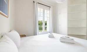 Une chambre d’hôtel avec un lit, une fenêtre avec des rideaux et une armoire.